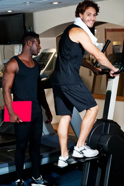 Young guy with his personal trainer beside him — Stock Photo, Image