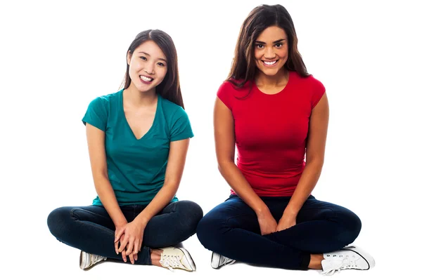 Young girls sitting on the floor, studio shot — Stock Photo, Image