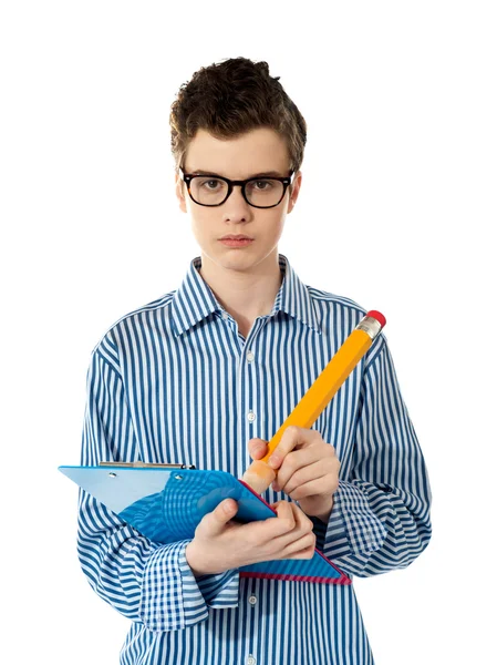 Serious young boy writing on a clipboard — Stock Photo, Image
