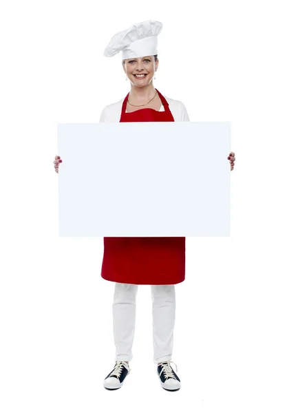 Female chef displaying blank white ad board — Stock Photo, Image