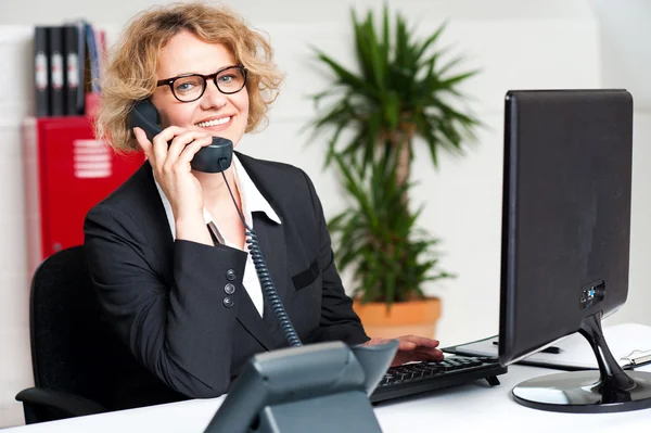 Happy front desk lady attending clients call — Stock Photo, Image