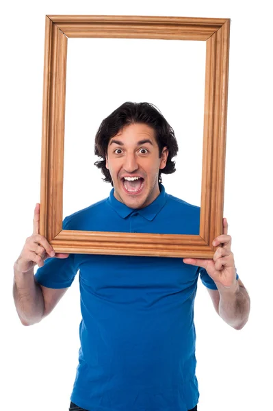 Excited young male holding wooden frame — Stock Photo, Image