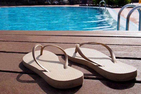 Par de zapatillas junto a una piscina — Foto de Stock