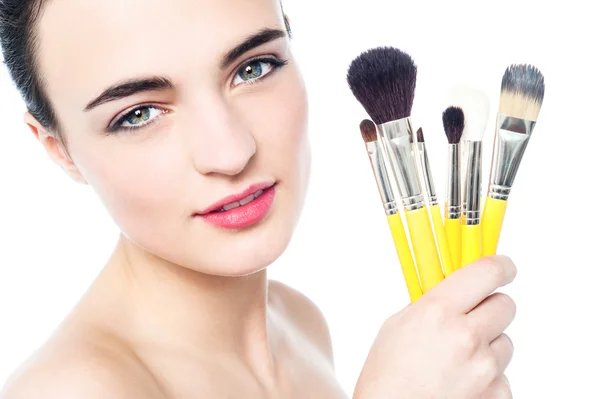 Mooi meisje met make-up borstels in de buurt van haar gezicht — Stockfoto