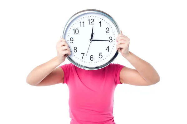 Chica tímida escondiendo su cara con reloj de pared — Foto de Stock