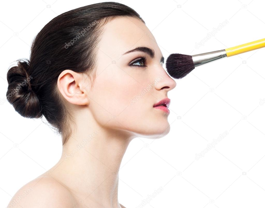 Pretty girl getting makeup applied on her face