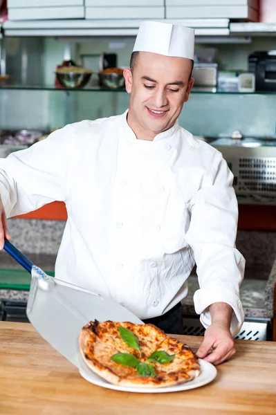 Chef-kok plaatsen pizza, klaar om te worden geserveerd. — Stockfoto