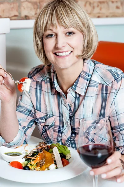 Donna assaporando il suo pasto con vino rosso — Foto Stock