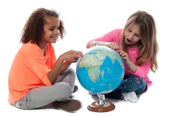 Jonge meisjes zoeken naar landen op wereldbol — Stockfoto