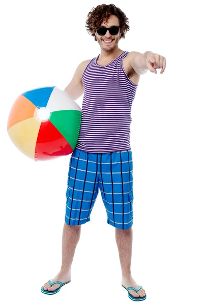 Веселый парень с пляжным мячом указывает на тебя — стоковое фото