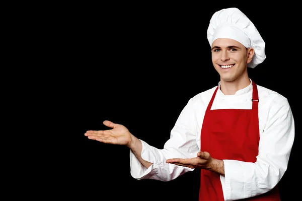 Usmívající se muž šéfkuchař prezentovat něco — Stock fotografie