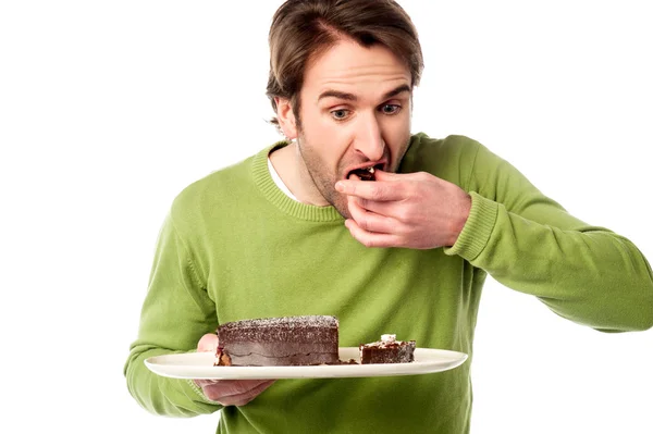 Young man tasting chocolate cake in hurry — Stock Photo, Image
