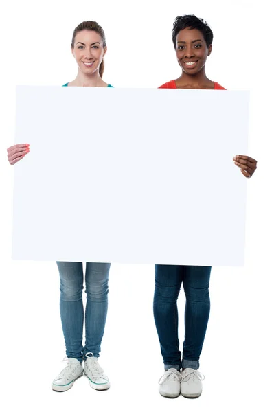 Mulheres casuais segurando quadro branco em branco — Fotografia de Stock
