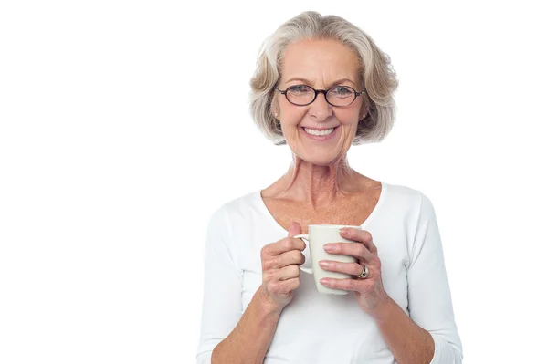 Smiling bespectacled old lady drinking coffee — Stock Photo, Image
