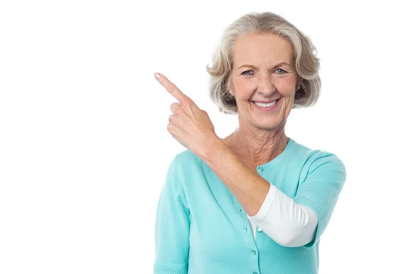 Pretty aged woman pointing at something — Stock Photo, Image