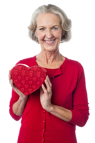 Mujer anciana sosteniendo una caja de regalo de San Valentín rojo — Foto de Stock