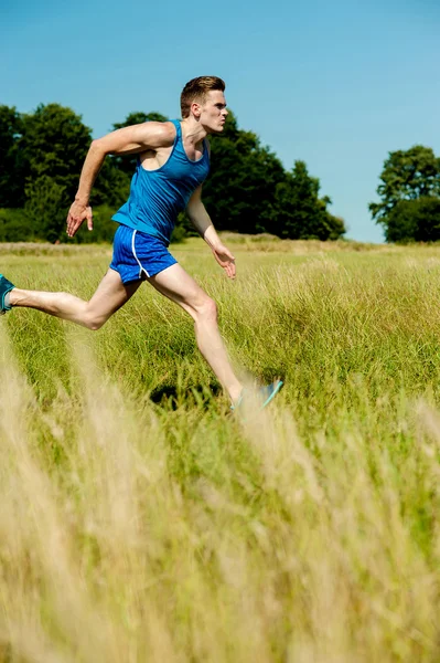 Young man running through meadows — Stock Photo, Image