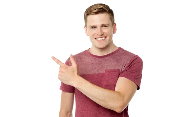Young cheerful man pointing away — Stock Photo, Image