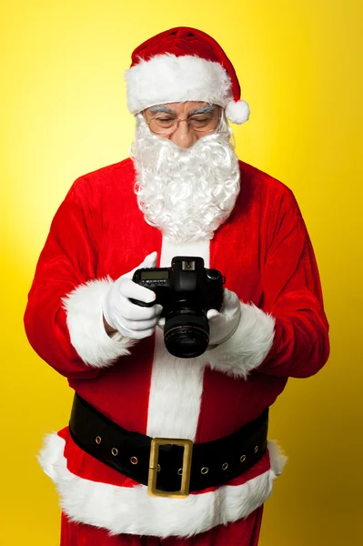 Santa verificando fotos em sua câmera DSLR — Fotografia de Stock