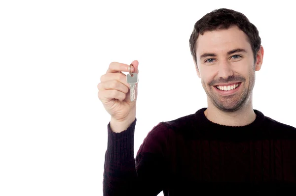 Usmívající se mladý muž ukazuje klíč — Stock fotografie