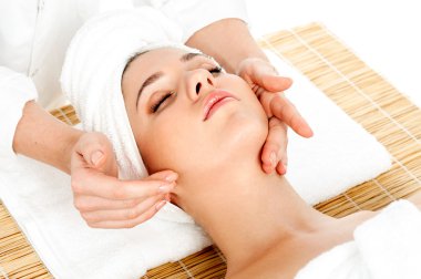 Kadın spa salonunda yüz masajı yaptırıyor.