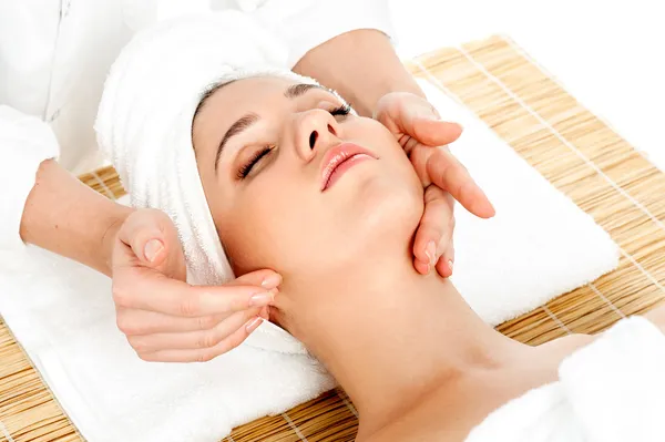Kadın spa salonunda yüz masajı yaptırıyor.