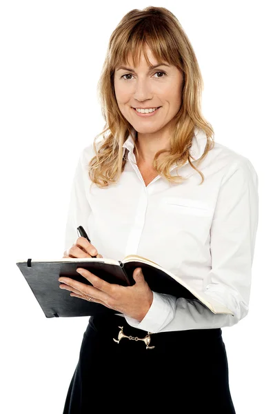 Vrolijke vrouwelijke assistent schrijven notities — Stockfoto