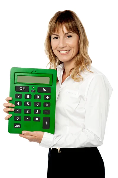 Lachende vrouw tonen grote groene rekenmachine — Stockfoto