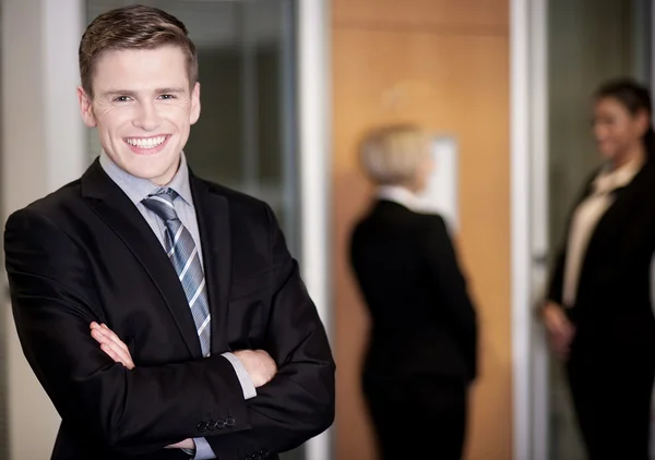 Geschäftsmann posiert mit smarten Mitarbeitern im Hintergrund — Stockfoto