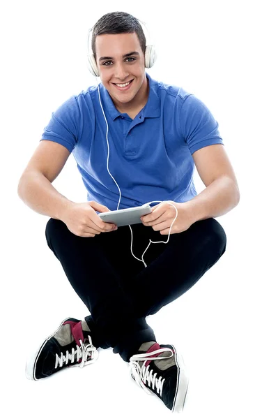 Young guy enjoying music and using tablet pc — Stock Photo, Image