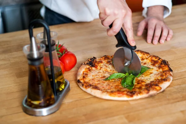 Chef-kok snijden pizza in stukjes — Stockfoto
