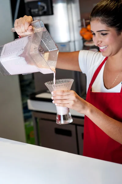 Girl filling glass with strawberry shake — Stock Photo, Image