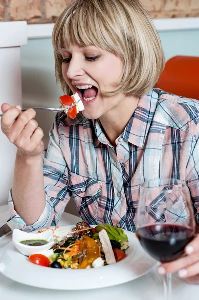 Γυναίκα απολαμβάνοντας το γεύμα της με κόκκινο κρασί — Φωτογραφία Αρχείου