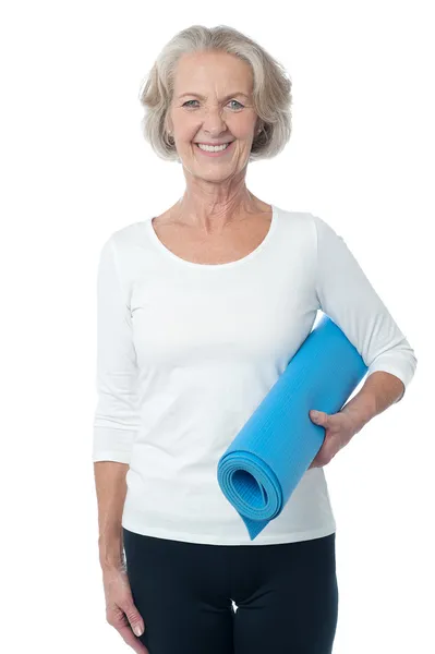 Instructor de gimnasio sosteniendo alfombra de ejercicio azul — Foto de Stock
