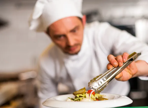 Chef arrangiert Salat in einer weißen Schüssel — Stockfoto