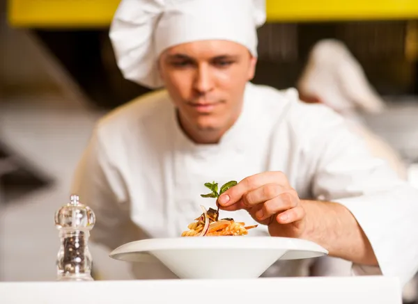 Chef décorant la salade de pâtes avec des feuilles de plantes — Photo