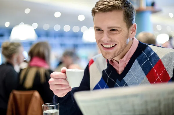 레스토랑에서 신문을 읽는 웃는 남자 — 스톡 사진