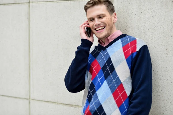 Happy man leaning against wall with cell phone — Stock Photo, Image