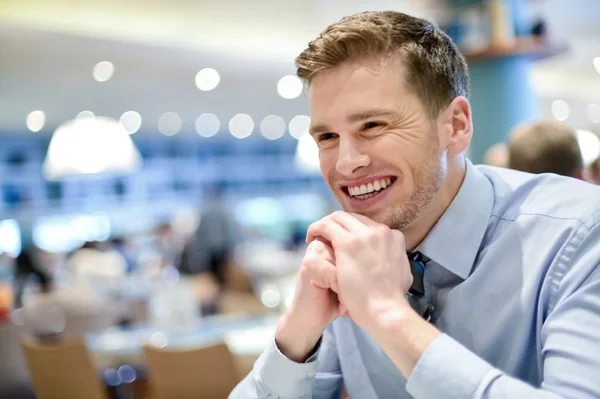 Lachende jonge man ontspannen in een café — Stockfoto