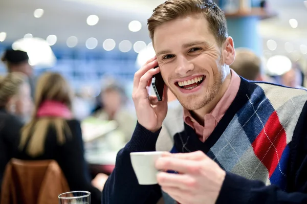 Νεαρός άνδρας που χρησιμοποιεί το κινητό τηλέφωνο στο καφέ — Φωτογραφία Αρχείου