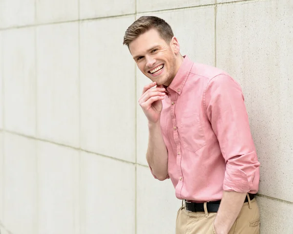 Feliz joven de pie contra la pared — Foto de Stock