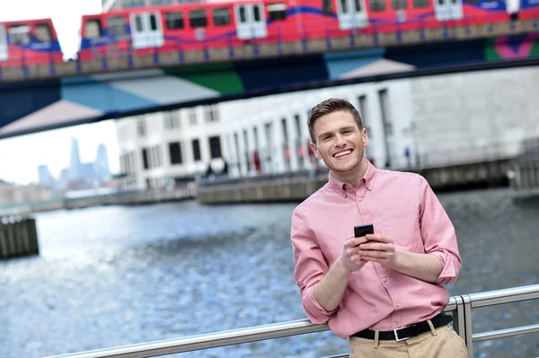 Bonito homem mensagens de texto em um telefone celular — Fotografia de Stock