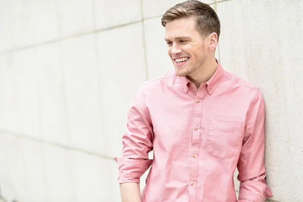 Happy young man standing against wall — Stock Photo, Image