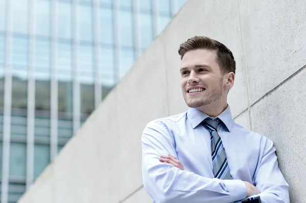 Smiling businessman standing against wall — Stock Photo, Image