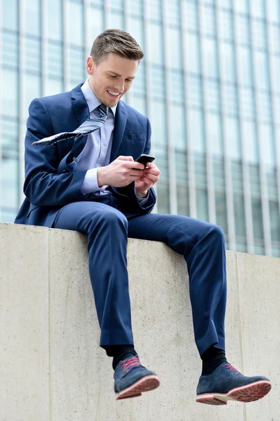 Улыбающийся бизнесмен со своим смартфоном — стоковое фото
