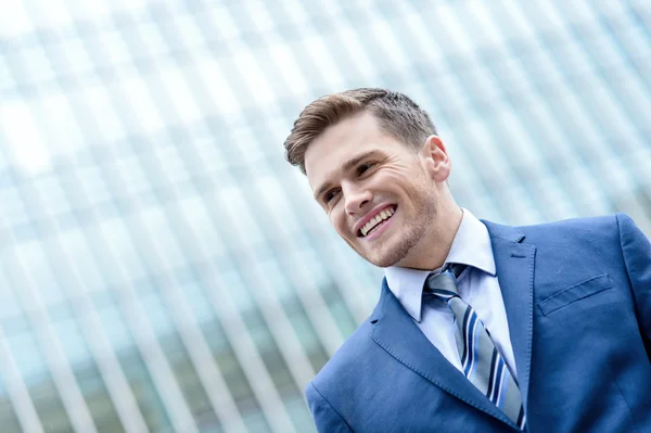 Jonge man op modern gebouw achtergrond glimlachen — Stockfoto