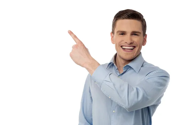 Happy young man pointing at something — Stock Photo, Image