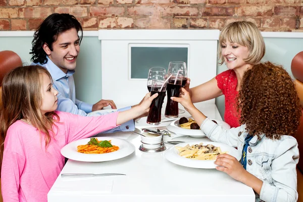 Família feliz em um restaurante clinking seus óculos — Fotografia de Stock