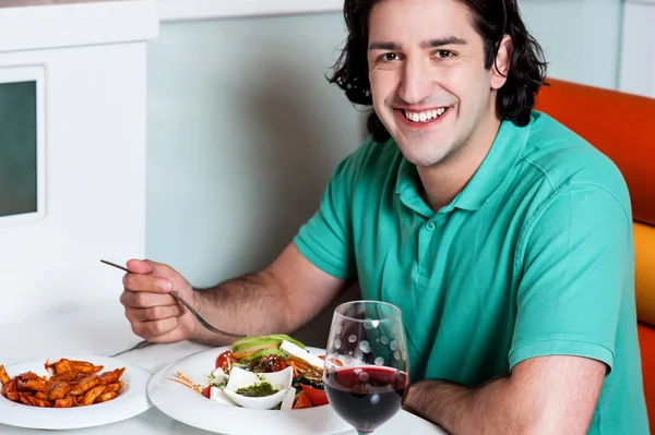 레스토랑에서 먹는 젊은 웃는 남자 — 스톡 사진