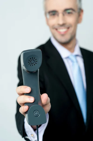 Young man holding phone receiver in hand and smiling Stock Image